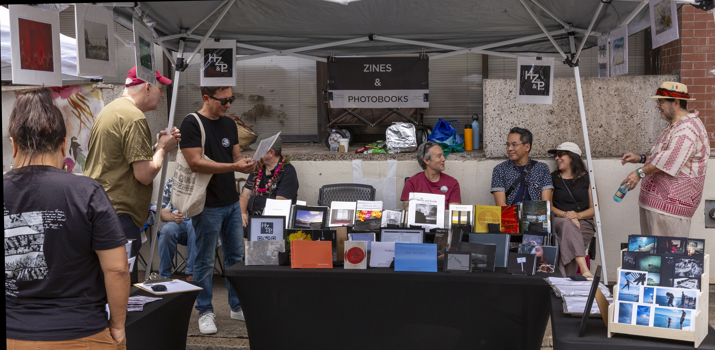 A member showing a zine to a visitor at the table