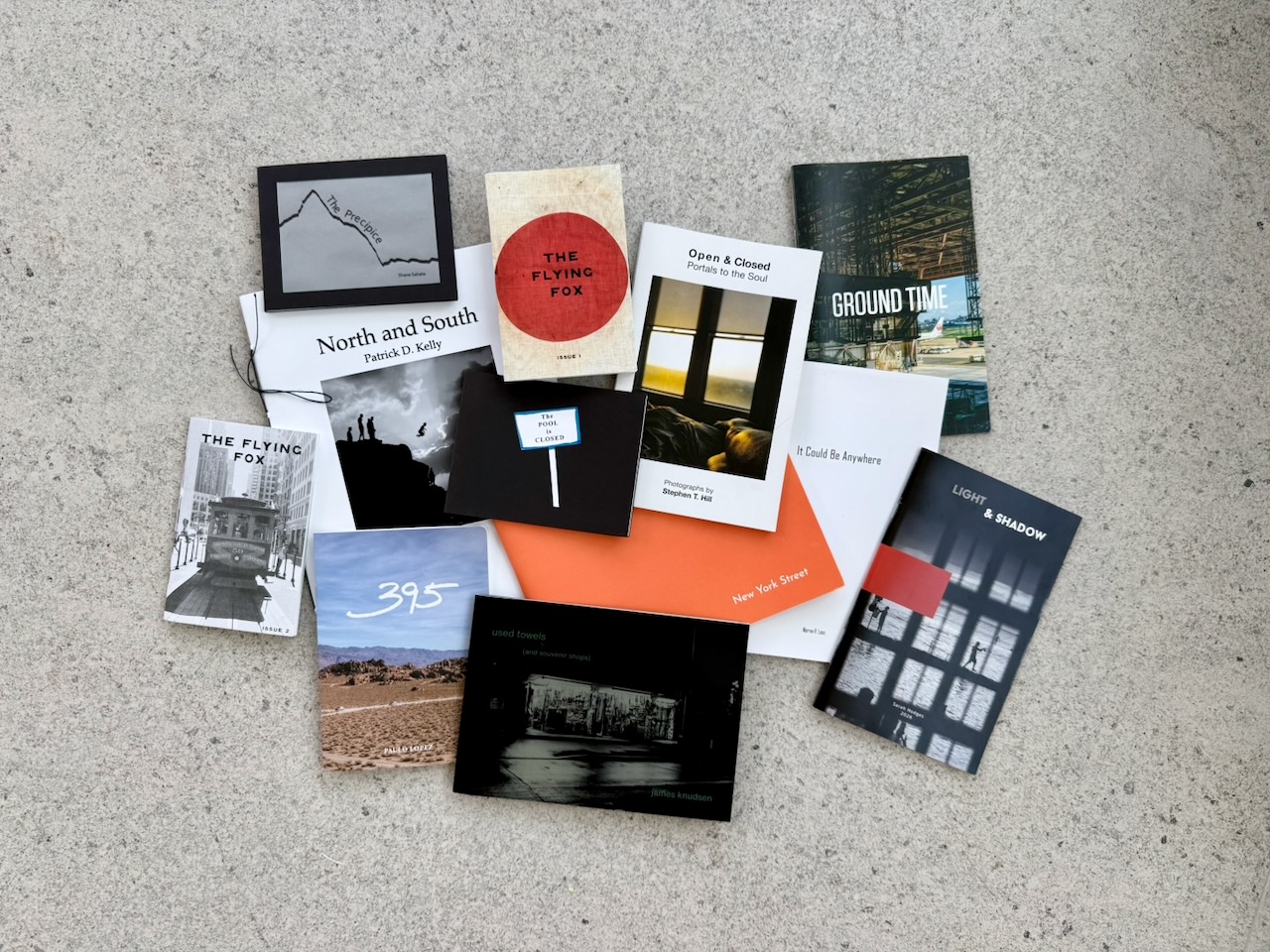 Zines from the 2026 table, shot flat on a white wall